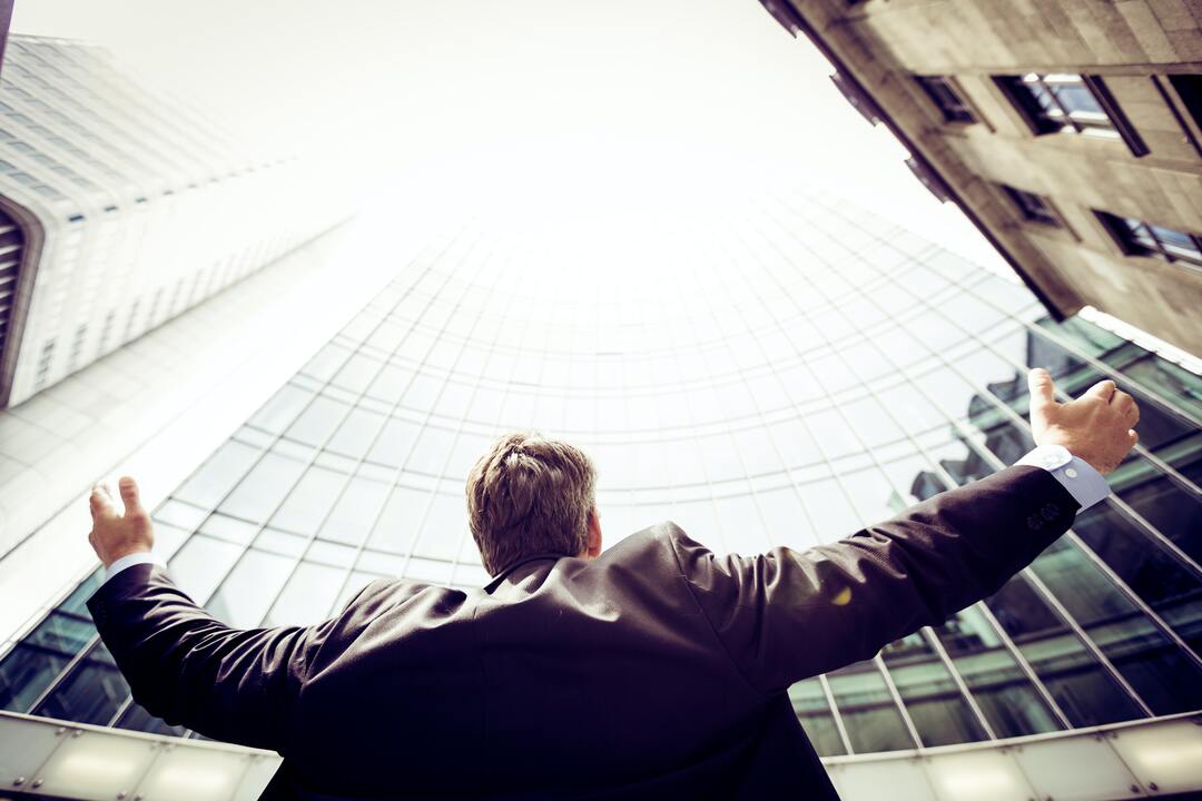 Mentalidade Global: imagem mostra homem de negócios com braços diante de prédios.